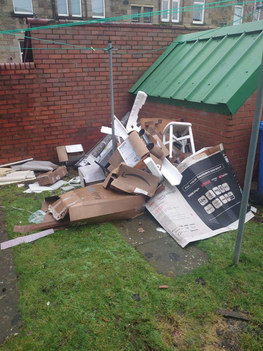 A pile of rubbish against an outbuilding